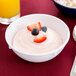 A Carlisle white melamine nappie bowl filled with yogurt and fruit.