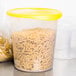 A Rubbermaid translucent plastic container with pasta and a yellow lid.