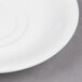 A close up of a 5 1/2" bright white porcelain saucer with a small rim.