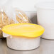 Two Rubbermaid white polyethylene food storage containers, one with a yellow lid and one with a white lid, on a counter.