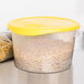 A Rubbermaid translucent plastic food storage container with pasta in it and a yellow lid.
