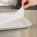 A hand placing a Baker's Mark parchment paper on a baking sheet.