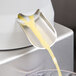 A Robot Coupe Cuisine Kit juicer pouring yellow juice into a glass.