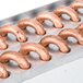 A copper condenser coil with metal rings on it.
