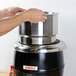 A person's hands putting an Avantco stainless steel pot into a black and silver container.