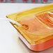 A Rubbermaid amber plastic food pan lid with a handle.