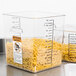 A Rubbermaid clear polycarbonate food storage container filled with pasta on a counter.