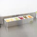 A San Jamar stainless steel condiment bar with six compartments holding different types of fruit.