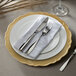 A white charger plate with a scalloped gold rim.