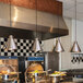 A school kitchen with Hanson Heat Lamps ceiling mount heat lamps above a large metal pot.