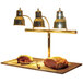 A Hanson Heat Lamps brass carving station with meat on a black surface.