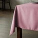 A pink Intedge square tablecloth on a table.