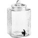 An Acopa clear glass beverage dispenser with a metal tap and lid.