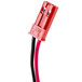 A close-up of a red and black cable with a red wire connected to a pink object.