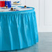 A table with a turquoise blue Creative Converting plastic table skirt on it.
