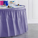 A purple Creative Converting plastic table skirt on a table with cupcakes.