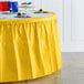 A Creative Converting School Bus Yellow plastic table skirt on a table with a yellow tablecloth.