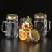 Three Libbey mason jars with gold metal lids filled with lemonade on a counter.