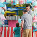 A man and two children using a Carnival King cotton candy machine with a stainless steel bowl.