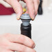 A person using a Vacu Vin wine stopper to close a bottle of wine.