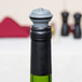 A close-up of a Vacu Vin wine bottle stopper in a black bottle.