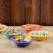 A table with four colorful Diamond Mardi Gras bowls of food.