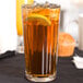 A Libbey paneled cooler glass of iced tea with a lemon slice and a lemon wedge.