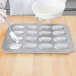 A person using a Chicago Metallic Madeleine pan to pour white batter into molds.
