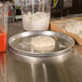 An American Metalcraft heavy weight aluminum deep dish pizza pan on a table with dough in it.