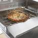 A pizza being cooked in a TurboChef electric countertop conveyor oven.