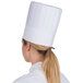 A woman wearing a Royal Paper pleated disposable chef hat.