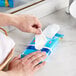 A person using a SC Johnson Windex glass wipe to clean a bathroom sink.