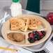 A Carlisle tan polycarbonate plate with waffles, fruit, and a drink on a tray.