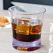 A Carlisle Alibi reusable plastic double rocks glass filled with a drink and ice cubes.