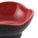 A black melamine bowl with a black and red pattern on the inside.