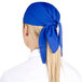 A woman chef wearing a royal blue adjustable bandana on her head.