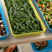 A yellow Cambro fiberglass market pan filled with green beans on a table in a salad bar.