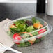A salad in a Dart clear plastic container with a clear dome lid.