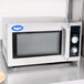 A Vollrath stainless steel commercial microwave on a counter with a glass door.