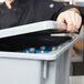 A person in a black jacket opening a grey Rubbermaid tote box lid.