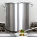 A Vollrath Wear-Ever aluminum stock pot with a spoon serving vegetables.