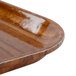 A close-up of a Cambro Burma Teak fiberglass tray with a wooden surface.