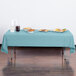 A table with a Creative Converting pastel blue plastic table cover on it, set with food.