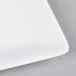 A close up of a 3" white square porcelain plate with a white rim.