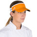 A woman in a white chef's coat wearing an orange Headsweats visor.