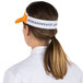 An orange and white Headsweats visor on a woman in a professional kitchen.