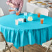 A table with a blue Creative Converting Bermuda Blue OctyRound plastic table cover and glasses of liquid.