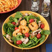 A bowl of shrimp and spinach salad in a Mardi Gras melamine bowl.