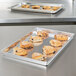 A Vollrath aluminum party pan filled with pastries on a counter.
