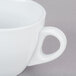 A close-up of a CAC white coffee cup with a handle.